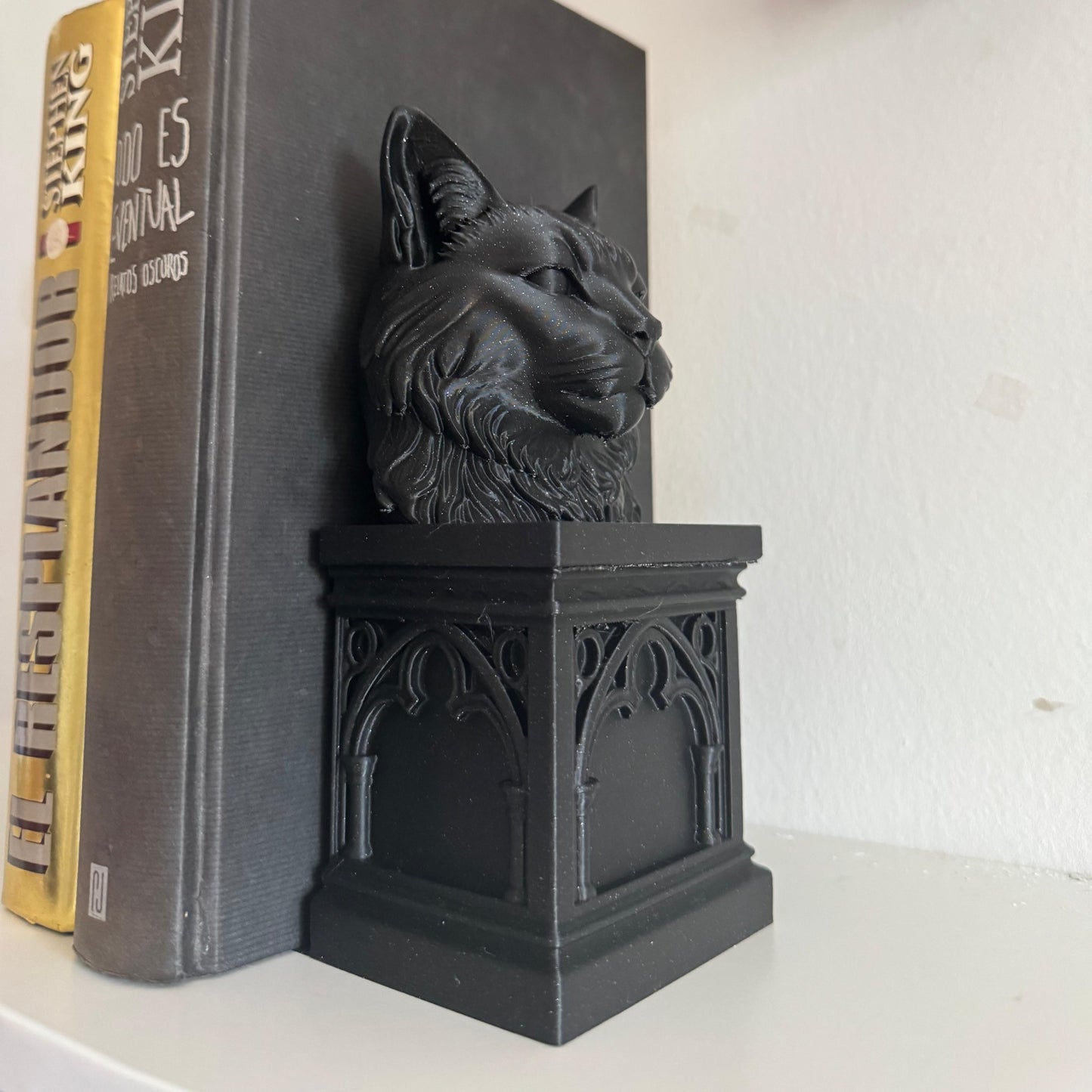 Black cat-shaped bookend on a book with a skull decoration in the background