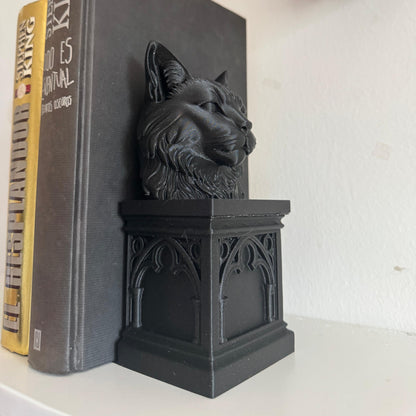 Black cat-shaped bookend on a book with a skull decoration in the background