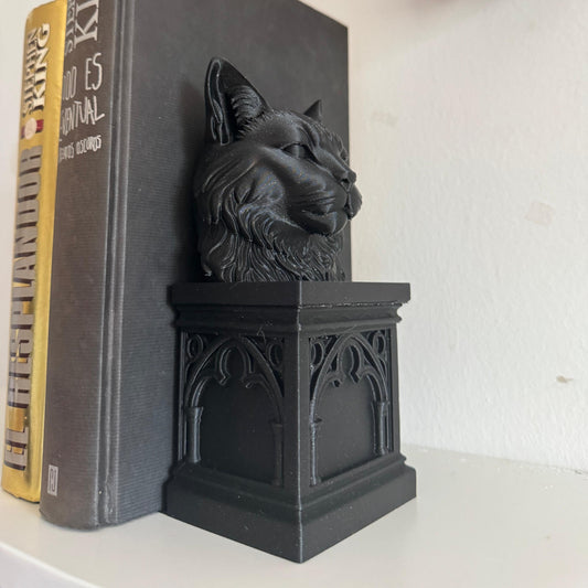 Black cat-shaped bookend on a book with a skull decoration in the background