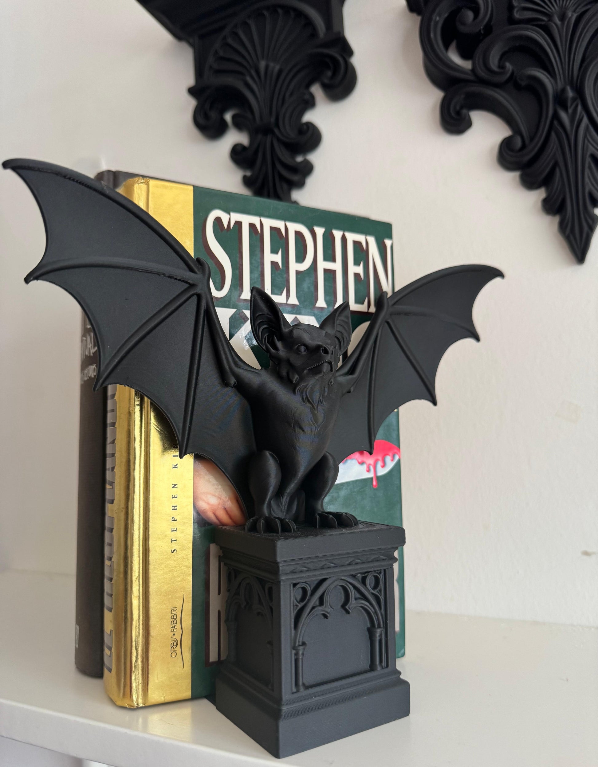 Black gargoyle bookend on a shelf with books